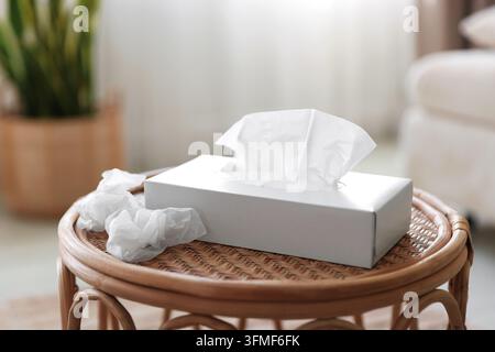 Porte-serviettes avec mouchoirs en papier et serviettes usagées sur la table à l'intérieur, gros plan Banque D'Images