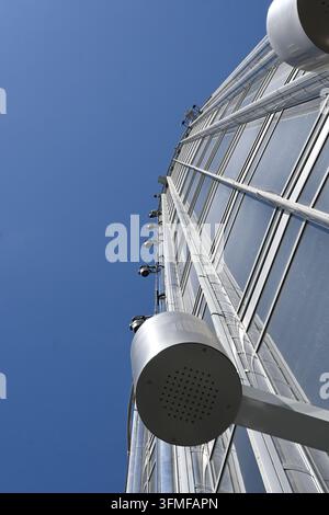 Une prise de vue en contre-plongée capture la structure imposante d'une grande roue contre un ciel bleu clair. Les panneaux de verre reflètent la lumière du soleil, créant une lumière vive Banque D'Images