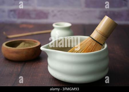Préparation du thé matcha avec fouet et bol sur une table en bois Banque D'Images