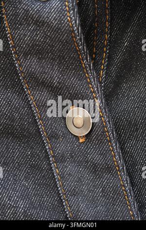 gros plan d'un bouton sur une chemise en jean sous une lumière naturelle Banque D'Images