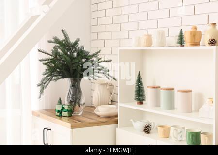 Intérieur de maison de Noël, décoration festive avec des branches de pin dans un vase et une petite boîte cadeau sur le comptoir de la cuisine dans un appartement moderne et lumineux Banque D'Images