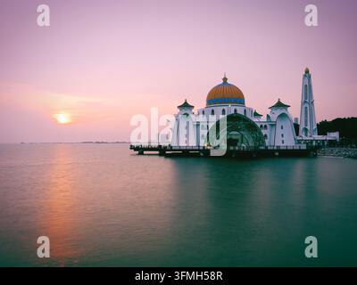 Mosquée flottante majestueuse avec dôme doré lors d'un coucher de soleil vibrant à Malacca, Malaisie Banque D'Images