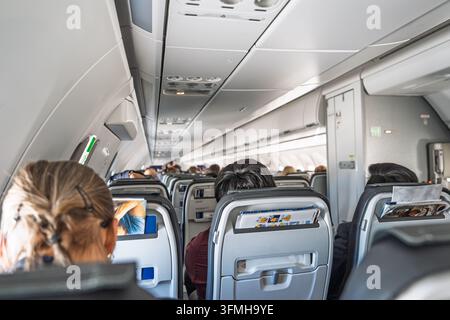 Vue intérieure d'une cabine d'avion commercial pendant un vol au-dessus de l'Espagne, montrant des passagers assis en classe économique. La scène reflète des aspects quotidiens Banque D'Images
