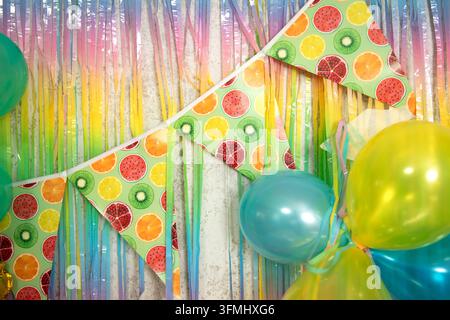 Fanions d'anniversaire colorés à motifs de fruits et ballons sur un fond de fête scintillant Banque D'Images