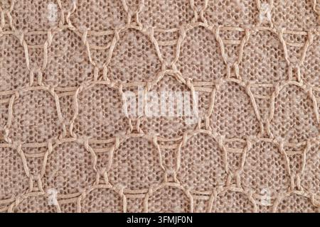 Gros plan d'un tissu tricoté beige montrant la texture de la laine et le motif tricoté à la main. Banque D'Images