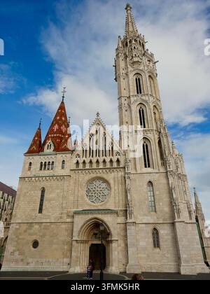 Le clocher gothique orné et le toit aux tuiles colorées en céramique de l'église Matthias s'élèvent majestueusement dans un ciel bleu sur la colline du château à Budapest. Banque D'Images