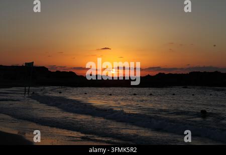 Beau coucher de soleil sur une colline de grès en silhouette, des rochers et la mer Méditerranée montrant des nuages d'automne, des motifs de lumière et de belles couleurs. Banque D'Images