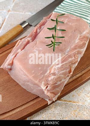 Rôti de porc frais cru sur une planche à découper Banque D'Images