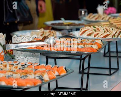 Une table de buffet avec des sushis et des sandwichs variés lors d'un événement traité à l'intérieur. Banque D'Images