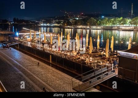 Les clients sont assis sur une terrasse de restaurant flottante illuminée sur la Vltava lors d'une nuit chaude dans la ville. Prague, République tchèque, 28 septembre 2026. Banque D'Images