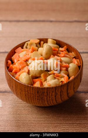Petits champignons entiers en conserve dans l'huile avec des morceaux de carotte, du sel et des épices. Champignons en conserve comme fond alimentaire pour votre conception Banque D'Images