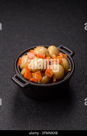 Petits champignons entiers en conserve dans l'huile avec des morceaux de carotte, du sel et des épices. Champignons en conserve comme fond alimentaire pour votre conception Banque D'Images