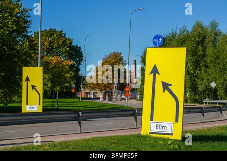 Panneaux de signalisation jaune temporaires indiquant un changement de voie à venir pendant les travaux de construction routière urbaine Banque D'Images