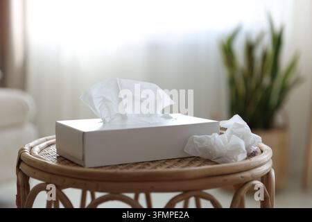 Porte-serviettes avec mouchoirs en papier et serviettes usagées sur la table à l'intérieur, gros plan Banque D'Images