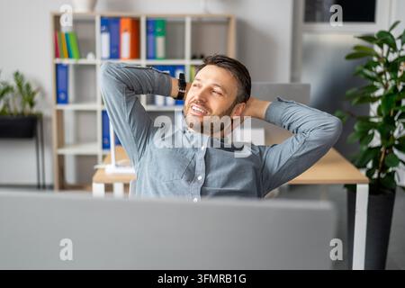 Homme caucasien souriant se détendant au bureau, profitant d'une pause travail, concept d'affaires Banque D'Images