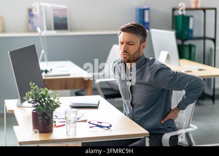 Homme souffrant de douleurs dorsales en travaillant à un bureau, concept de perte de poids Banque D'Images