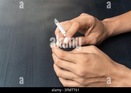 Un gros plan d'une main humaine tenant une cigarette allumée. Banque D'Images