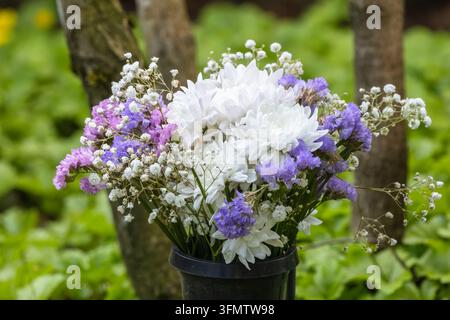 Un beau bouquet commémoratif dans un cimetière. Le bouquet contient des fleurs blanches, bleues et violet clair. Fond flou. Banque D'Images