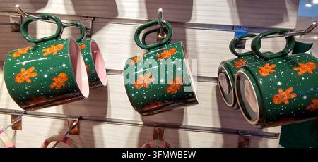 Tasses de Noël vertes avec des figurines en pain d'épices et des motifs blancs festifs suspendues à des crochets de présentation dans un magasin à Granada, en Espagne. Banque D'Images