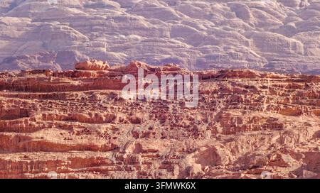Vue des formations rocheuses en grès escarpées du désert de Wadi Rum, présentant des textures érodées et des falaises stratifiées sous une lumière vive à Wadi Rum Banque D'Images