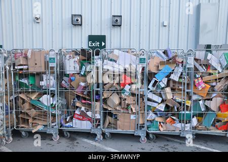 Cages à rouleaux en métal / cages à 4 côtés avec carton et déchets d'emballage alignés à l'extérieur d'un bâtiment de supermarché sous un panneau de sortie. Recyclage commercial Banque D'Images