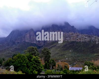 Vue des montagnes abruptes du Langeberg avec des pics dramatiques partiellement obscurcis par des nuages bas, des pentes verdoyantes et une végétation indigène à Montagu, W Banque D'Images