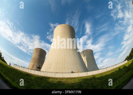 Vue des grandes tours de refroidissement en béton d'une centrale nucléaire sous un ciel bleu éclatant parsemé de nuages fins en Tchéquie. Banque D'Images