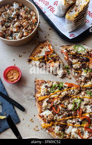 Offre de restauration rapide proposant un repas copieux avec des tranches de pizza au poulet, un wrap et un bol de riz au poulet Banque D'Images