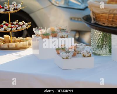 Diverses snacks d'apéritif présentés sur des supports blancs sur une table. Banque D'Images