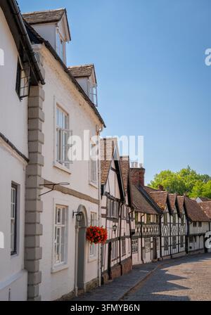 Anciennes maisons de Mill Street à Warwick, Royaume-Uni, avec des fleurs rouges dans un panier suspendu. Banque D'Images