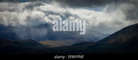 Panorama aérien des montagnes de Cairngorm sous un ciel orageux, avec des averses de pluie, un ciel nuageux bas et des rayons de lumière, Parc national des Cairngorms, Écosse Banque D'Images