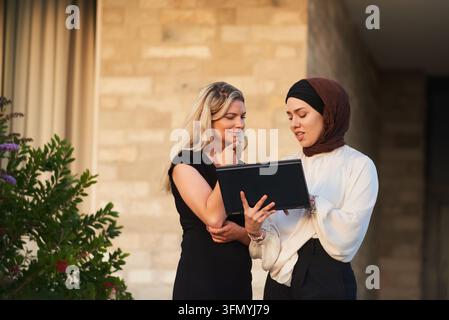 Deux collègues d'affaires discutant du travail sur un ordinateur portable lors d'une réunion en plein air Banque D'Images
