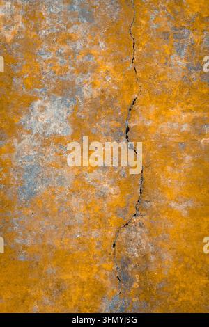 Gros plan d'un mur en plâtre orange et gris patiné avec une fissure verticale au Palais de Pena à Sintra, au Portugal, capturant la texture de l'architecture historique Banque D'Images
