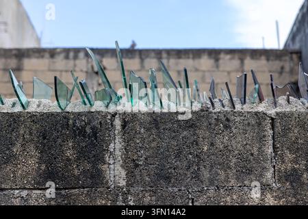 Tessons de verre brisés encastrés au sommet d'un mur de béton – Barrière de sécurité anti-vol Banque D'Images