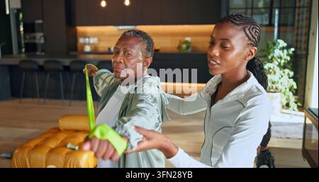 Personal trainer, bandes de résistance et fitness avec des femmes noires à la maison pour l'aide, la santé et le soutien gériatriques. Thérapie physique, réhabilitation et Banque D'Images