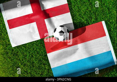 Match de football Angleterre contre Luxembourg. Drapeaux nationaux sur l'herbe verte avec un ballon de football au centre. Fond de football pour un match international. Banque D'Images