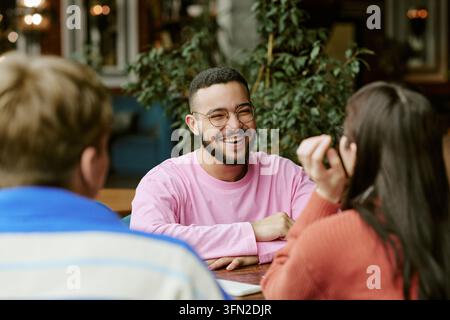 Amis divers et heureux discutant et riant dans un café moderne Banque D'Images