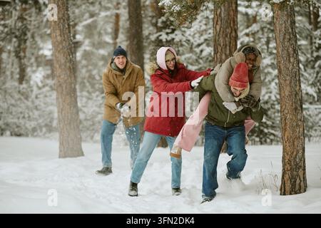 Des amis divers profitant d'un tour à califourchon dans une forêt enneigée en hiver Banque D'Images