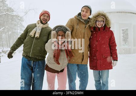 Des amis divers s'amusant et riant en plein air en hiver Banque D'Images