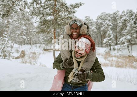Portrait d'un homme donnant un tour sur ses épaules à une femme noire dans un parc hivernal Banque D'Images