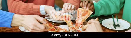 En-tête d'un groupe divers d'amis prenant des parts de pizza dans un café Banque D'Images