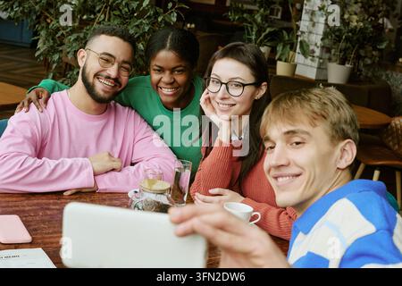 Portrait d'amis multiethniques prenant un selfie avec un smartphone dans un café Banque D'Images