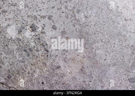 Un fond en vue de dessus détaillé d'une surface en béton gris rugueux montrant une texture naturelle usée, de petites pierres et un motif industriel pour des projets de design. Photo de haute qualité Banque D'Images