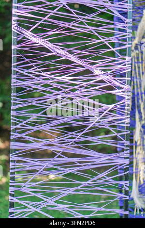 Gros plan d'une œuvre d'art moderne abstraite en orientation verticale, mettant en valeur des mèches fluides violettes et bleues Situé éventuellement à l'extérieur ou près d'une fenêtre Banque D'Images