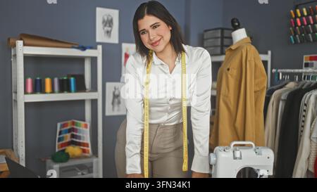 Couturière tenant un mètre ruban autour du cou en ajustant le tissu dans l'atelier de couture ; confiance créative. Banque D'Images