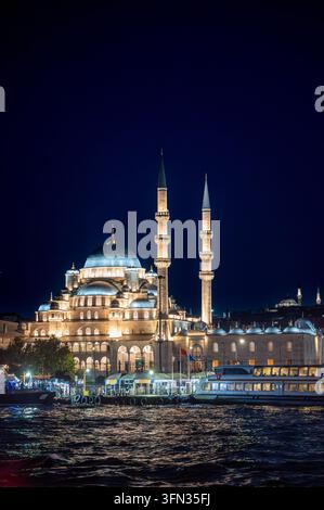 Istanbul, Turquie, 4 août 2025. La mosquée Yeni Cami montre son architecture historique et ses minarets, brillamment éclairés la nuit par le Bosphore à Eminönü Banque D'Images