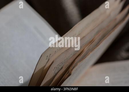 Livre ouvert affichant des pages vieillies et texturées avec une écriture à peine visible, évoquant des concepts d'histoire, d'apprentissage et de littérature vintage Banque D'Images