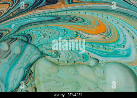 Close-up de lignes de peinture acrylique tourbillonnantes turquoise et orange avec des bulles d'huile flottantes et texture Banque D'Images