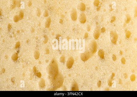 Vue macro de la surface d'une éponge jaune montrant une texture poreuse détaillée Banque D'Images