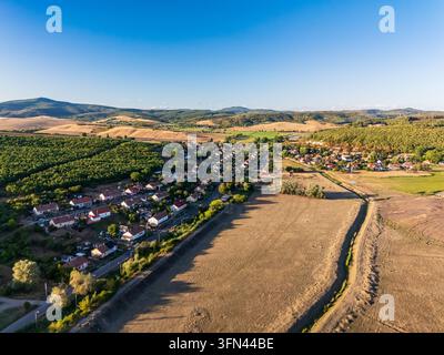 Vue aérienne du village de Rakoczibanya parmi les champs cultivés, les vergers et les collines boisées des monts Matra, en Hongrie, par une claire journée de fin d'été. Banque D'Images
